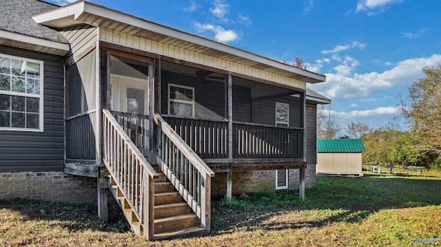 exterior space featuring a sunroom, a yard, and a storage shed