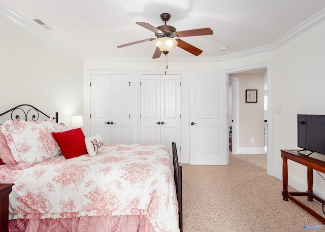 bedroom with ornamental molding, light carpet, ceiling fan, and multiple closets