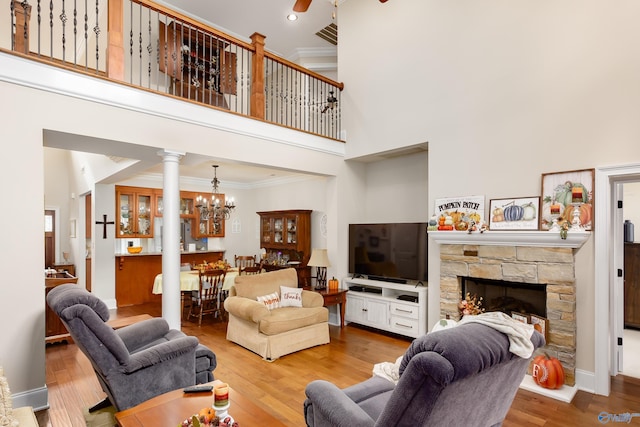 living room with a fireplace, hardwood / wood-style flooring, crown molding, and a towering ceiling