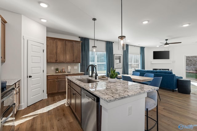 kitchen featuring sink, dishwasher, hanging light fixtures, a center island with sink, and dark hardwood / wood-style flooring