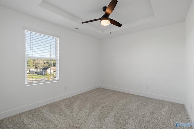 carpeted empty room with a raised ceiling and ceiling fan