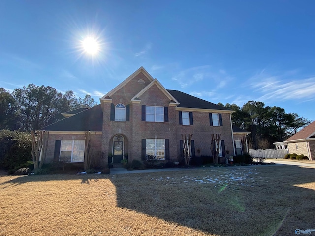 view of front of home featuring a front yard, fence, and brick siding