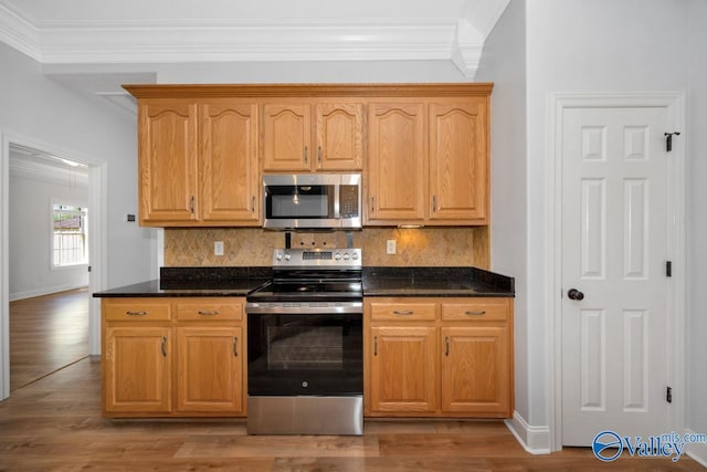 kitchen with stainless steel appliances, light wood-type flooring, crown molding, baseboards, and tasteful backsplash