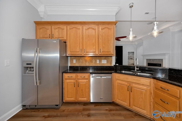 kitchen featuring dark wood finished floors, a sink, crown molding, tasteful backsplash, and appliances with stainless steel finishes