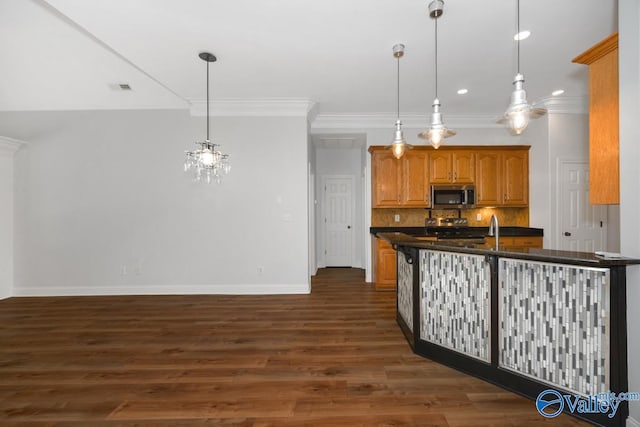 kitchen featuring stainless steel microwave, baseboards, dark countertops, and crown molding
