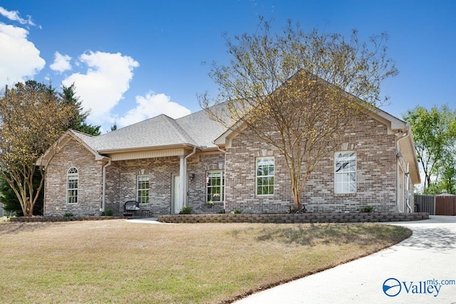 single story home featuring fence, brick siding, and a front yard