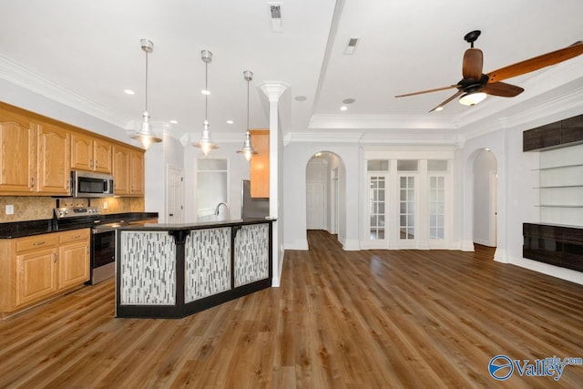 kitchen with a ceiling fan, arched walkways, dark countertops, and stainless steel appliances