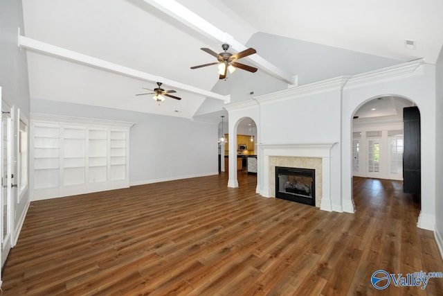 unfurnished living room with beamed ceiling, a ceiling fan, arched walkways, and a tile fireplace