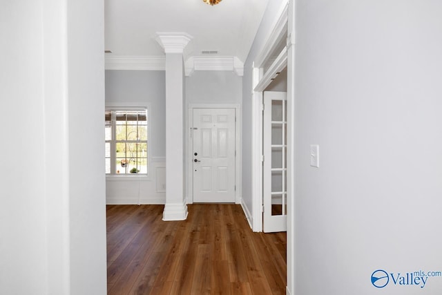 foyer featuring crown molding, wood finished floors, and decorative columns