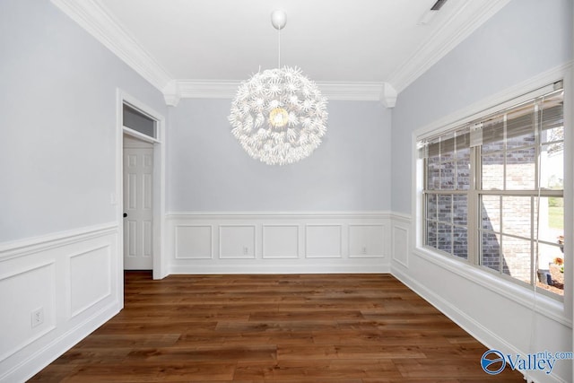 unfurnished dining area featuring wainscoting, ornamental molding, a notable chandelier, and dark wood-type flooring