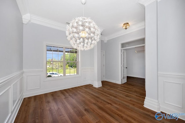 unfurnished dining area with wainscoting, an inviting chandelier, crown molding, and dark wood-type flooring