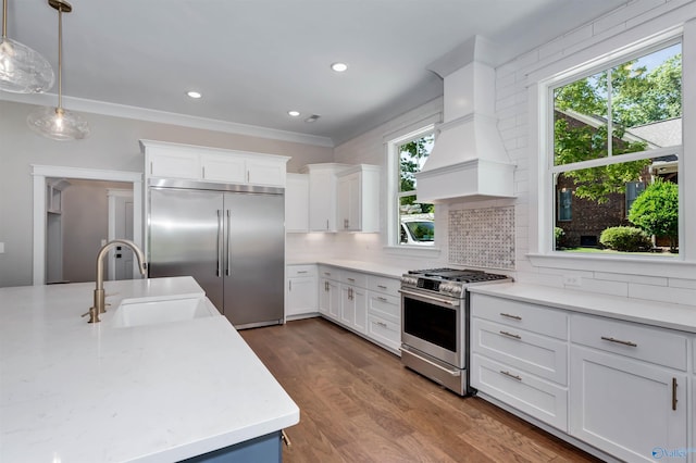 kitchen featuring stainless steel appliances, white cabinets, pendant lighting, sink, and custom exhaust hood