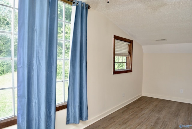 interior space featuring vaulted ceiling, a textured ceiling, and hardwood / wood-style floors