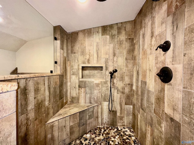 bathroom with a tile shower and vaulted ceiling