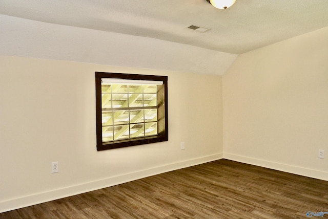 unfurnished room featuring a textured ceiling, dark hardwood / wood-style flooring, and lofted ceiling