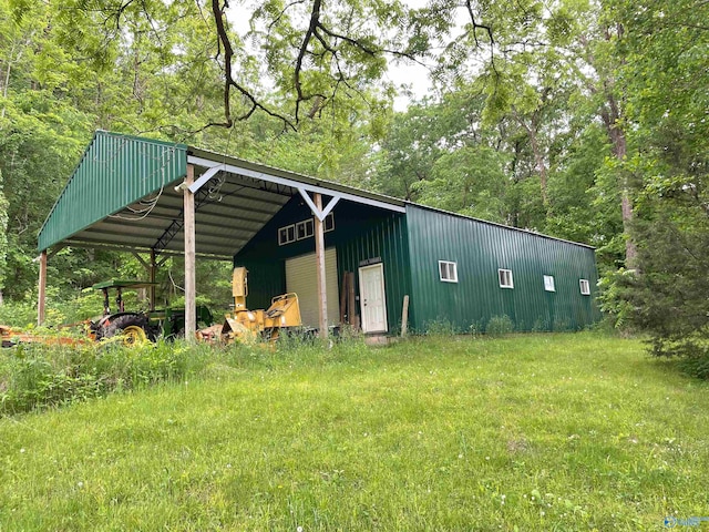 view of outdoor structure with a carport and a lawn