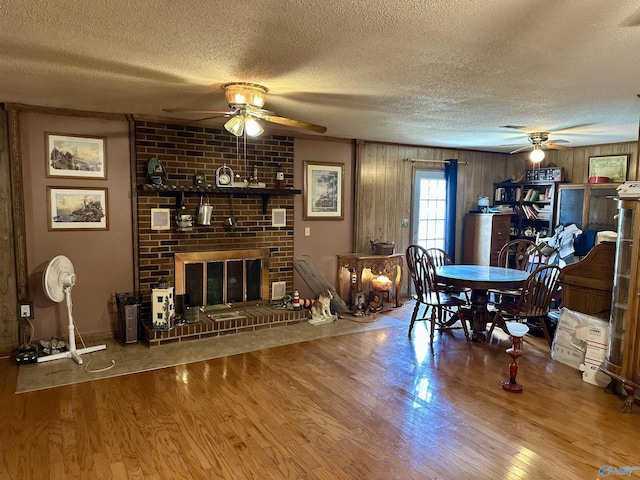 1212 Twin Lake Cir SW, Hartselle, AL 35640 - living area featuring a ceiling fan, a textured ceiling, wood finished floors, a brick fireplace, and wood walls