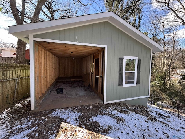 snow covered structure with an outbuilding and fence