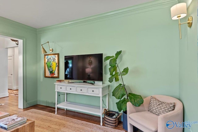 living area with baseboards, wood finished floors, and crown molding