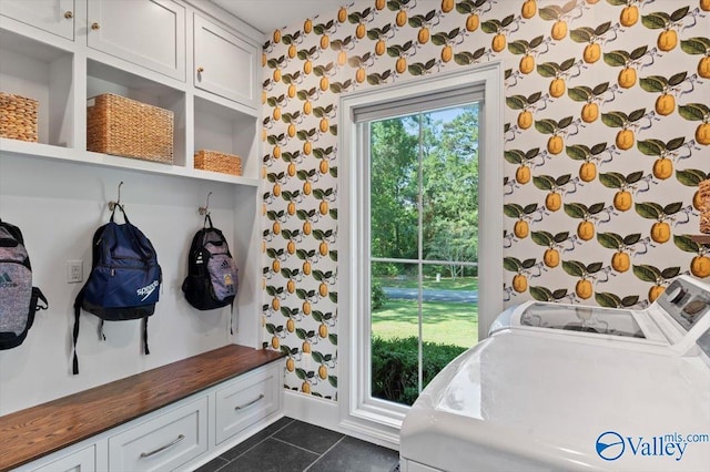 mudroom with dark tile patterned floors, washing machine and dryer, and a wealth of natural light