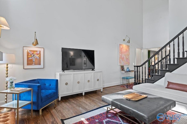 living room with stairs, a high ceiling, wood finished floors, and baseboards