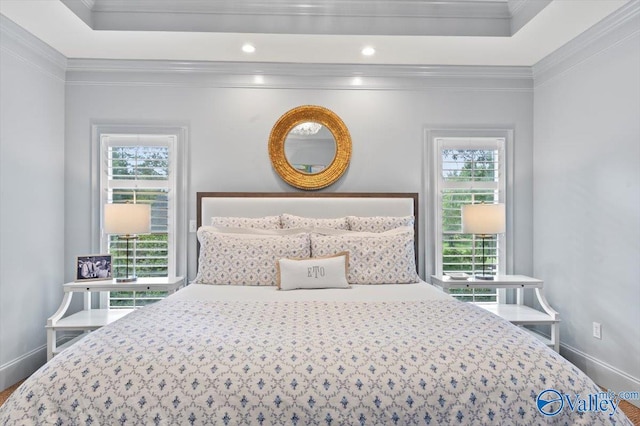 bedroom featuring a raised ceiling, crown molding, and baseboards