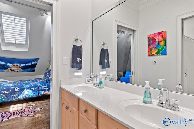 ensuite bathroom with wood finished floors, connected bathroom, a sink, and double vanity