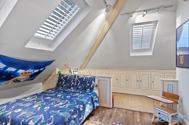 bedroom featuring lofted ceiling with skylight, wood finished floors, and rail lighting