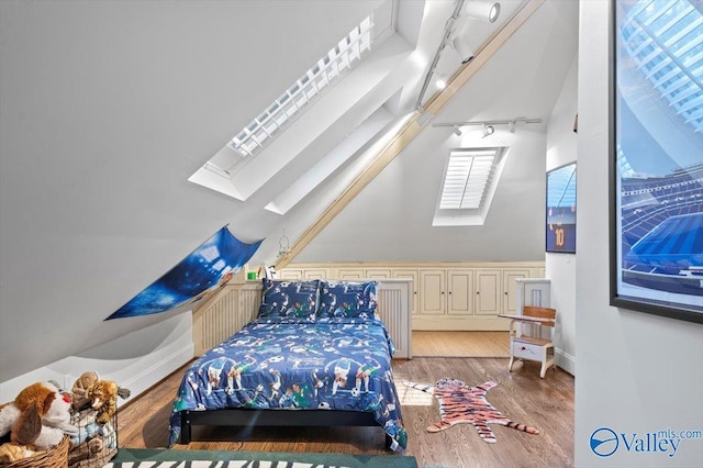 bedroom featuring lofted ceiling with skylight, rail lighting, and light wood-style flooring