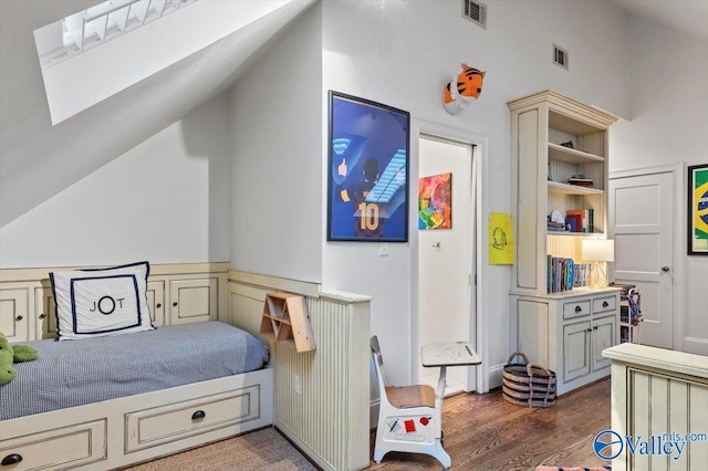 bedroom with vaulted ceiling, wood finished floors, and visible vents