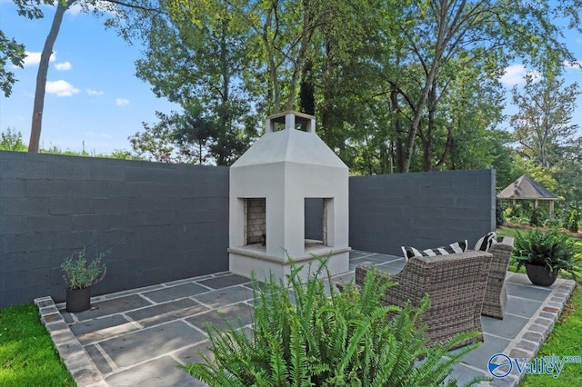 exterior space featuring a patio area, fence, an outdoor fireplace, and stucco siding