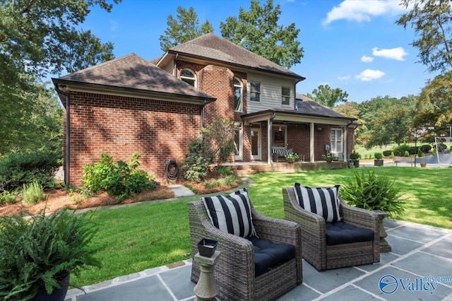 rear view of house with a yard, brick siding, and a patio area