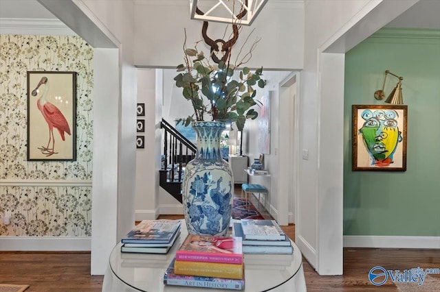 interior space featuring wallpapered walls, crown molding, baseboards, and wood finished floors