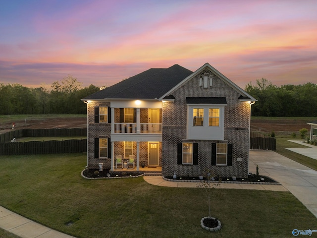 traditional home with brick siding, a yard, concrete driveway, and a balcony