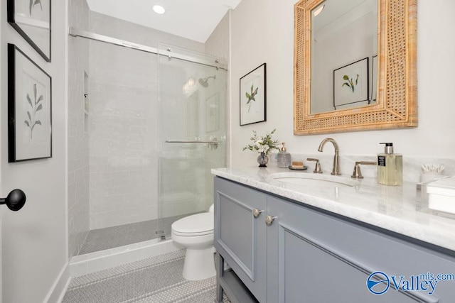 bathroom featuring vanity, a shower with shower door, tile patterned floors, and toilet