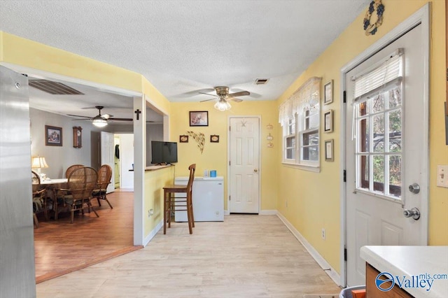 interior space with light wood-type flooring, ceiling fan, and a textured ceiling