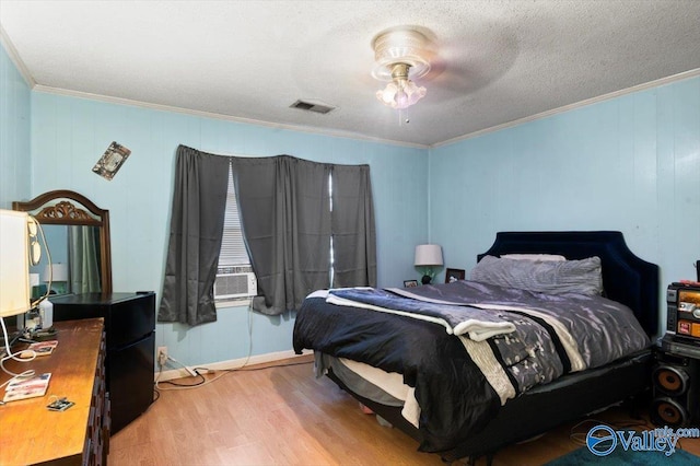 bedroom featuring wood-type flooring, a textured ceiling, ceiling fan, and ornamental molding