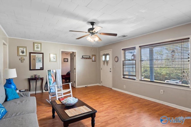 living room featuring hardwood / wood-style flooring, ornamental molding, and ceiling fan