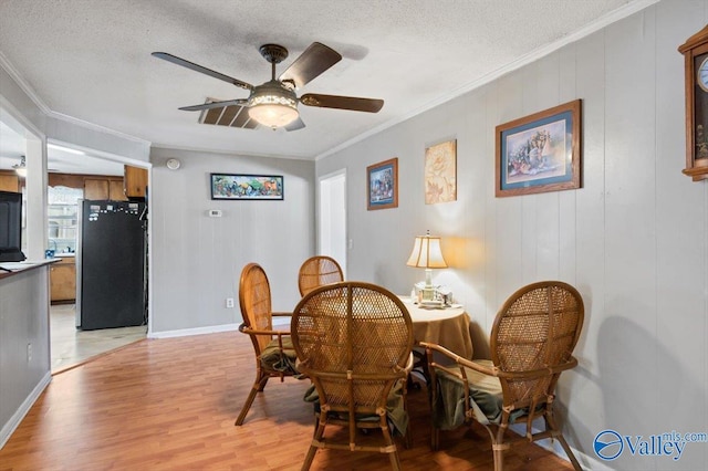 dining area featuring ornamental molding, light hardwood / wood-style floors, and a textured ceiling