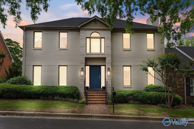 view of front of house featuring entry steps, brick siding, and a front lawn