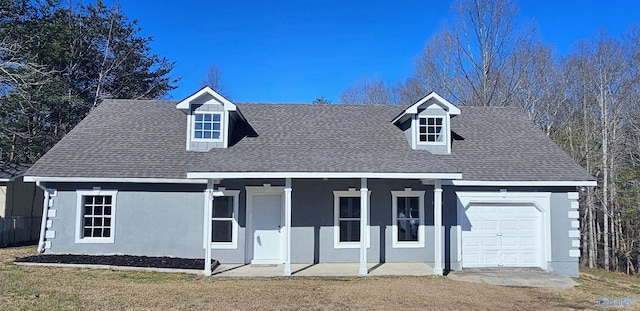 cape cod house featuring a garage, roof with shingles, covered porch, a front lawn, and stucco siding