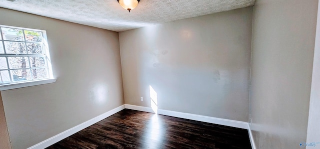 empty room with a healthy amount of sunlight, baseboards, dark wood finished floors, and a textured ceiling