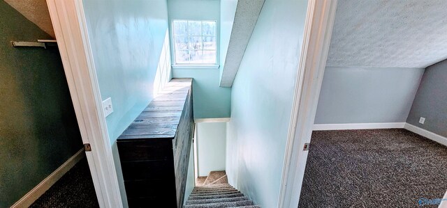 stairs featuring carpet floors, vaulted ceiling, a textured ceiling, and baseboards