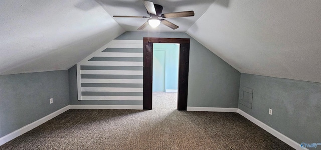 additional living space featuring dark colored carpet, vaulted ceiling, a textured ceiling, and baseboards