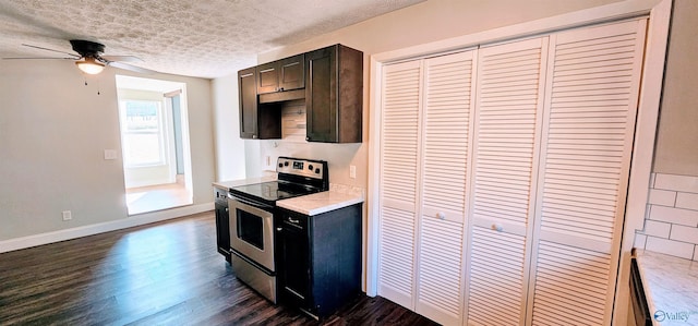 kitchen with dark wood finished floors, stainless steel electric range, light countertops, a textured ceiling, and baseboards