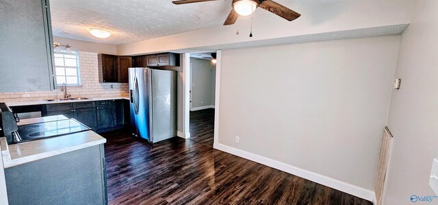 kitchen featuring decorative backsplash, dark wood-style flooring, light countertops, stainless steel refrigerator with ice dispenser, and a sink