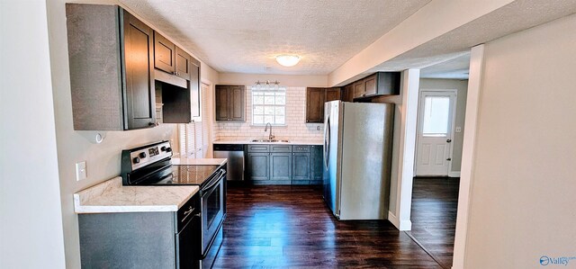 kitchen with stainless steel appliances, dark wood-style flooring, a sink, light countertops, and tasteful backsplash