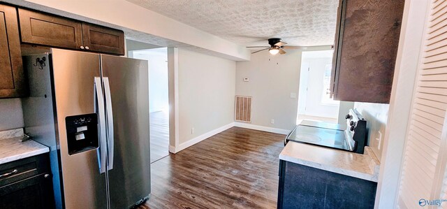 kitchen with a textured ceiling, dark wood-type flooring, range with electric cooktop, visible vents, and stainless steel fridge