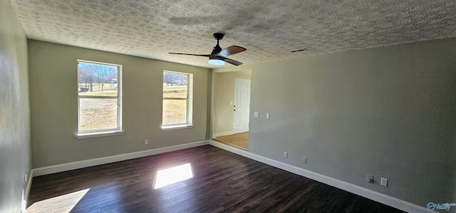 spare room with visible vents, dark wood-type flooring, a ceiling fan, a textured ceiling, and baseboards