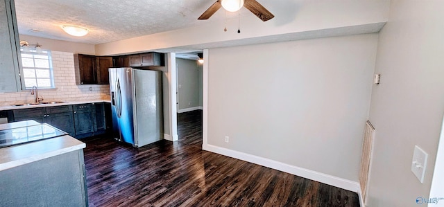 kitchen featuring tasteful backsplash, light countertops, dark wood-type flooring, a sink, and stainless steel fridge